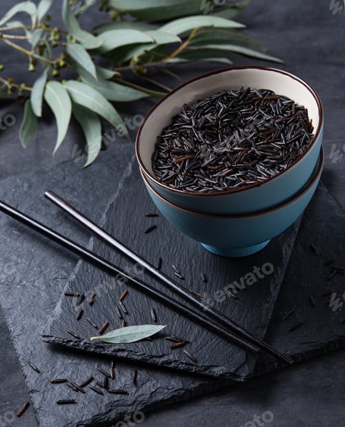 Preview: black rice in a blue bowl on a slate Board on a black background