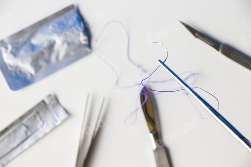 Preview: Selective focus of a surgical needle and thread with a dissection kit on a white background