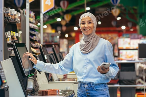 Preview: Self-service in a supermarket. A young Arab woman in a hijab is standing near the electronic cash