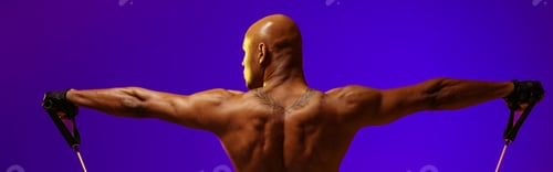 Preview: Back view of man performs exercises with expander on studio background. Strength and motivation