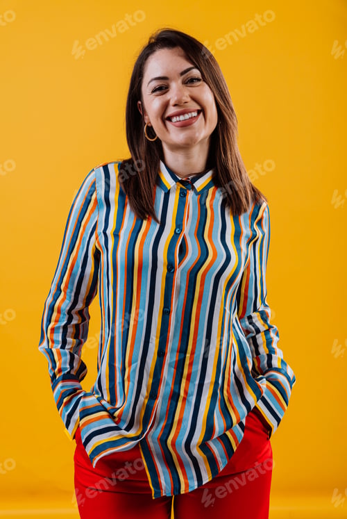 Preview: Smiling woman posing in colorful striped shirt on yellow background