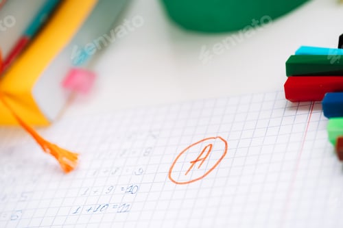 Preview: Excellent score next to the correct solution on a piece of paper in front of school supplies