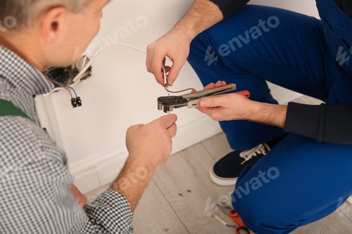 Preview: Electrician and apprentice working with wires indoors, closeup