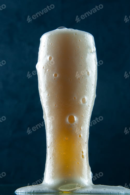 Preview: Closeup of overflowing glass cup of beer on dark blue background