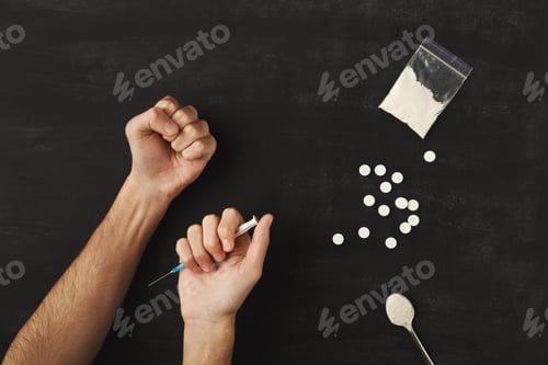 Preview: Drug addict hands holding syringe for injection on dark table