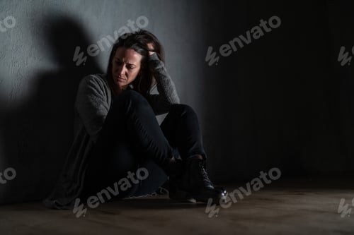 Preview: Sad mid-adult woman, alone in darkness, sitting and thinking
