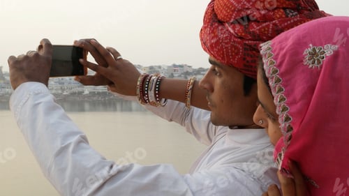 Preview: Closeup of an Indian couple in traditional outfits taking pictures of the Ganges.