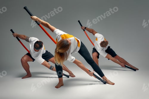 Preview: Two men and woman aikido fighters with wooden fight stick posing in studio, fight demonstration