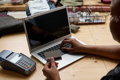 Preview: Hand of young African American woman with credit card over laptop keyboard