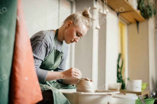 Visualização: Mulher oleira moldando paredes de louça de barro na roda de oleiro