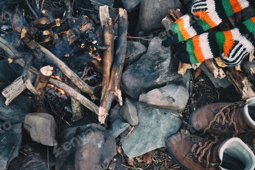 Preview: Knitted socks and hiking boots drying near a campfire