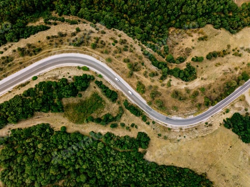 Preview: Aerial above view of a rural landscape with a curvy road running through it in Greece.