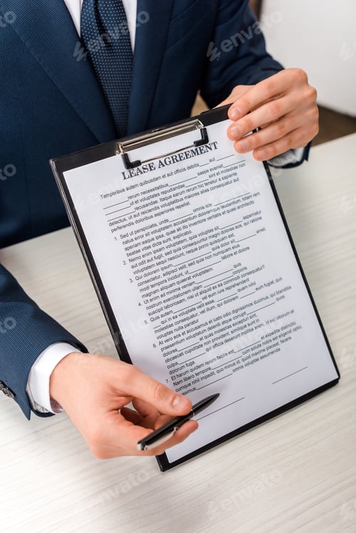 Preview: cropped view of agent holding clipboard with lease agreement lettering near desk