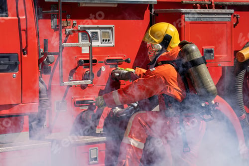 Preview: Firefighter wearing fire protection suite and oxygen tank exercise roll hose connect with fire truck