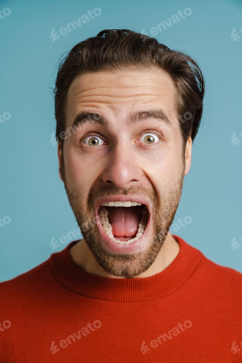 Preview: Young shocked man wearing red sweater screaming at camera