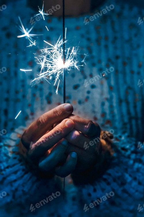 Preview: New year eve christmas celebration concept with close up of hands holding firework sparkler