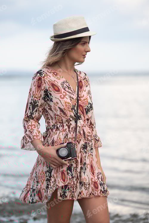 Preview: Fashionable Caucasian woman holding camera and photographing scenery at the beach. Lifestyle people