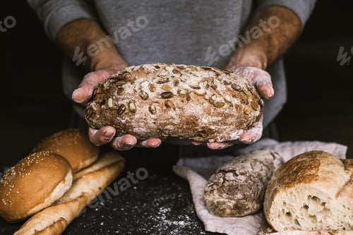 Preview: Baker man holding a rustic organic loaf of bread in his hands