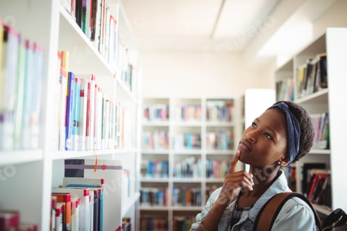 Preview: Schoolgirl selecting book from book shelf in library