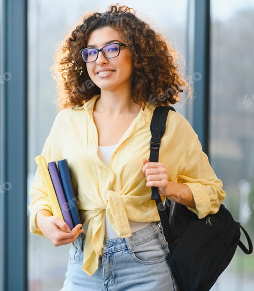 Preview: Female student holding books and backpack smiling