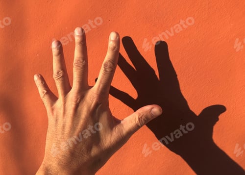 Preview: a hand and its shadow with orange wall background