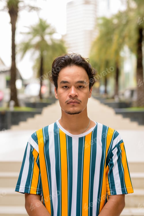 Preview: Portrait of handsome multi-ethnic young man wearing colorful shirt outdoors during summer