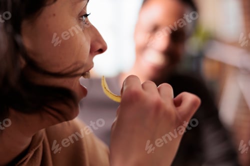 Preview: Close up shot of happy woman eating chips while sitting at home with multiethnic friends.