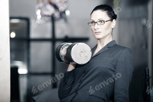 Preview: Serious businesswoman with heavy barbell