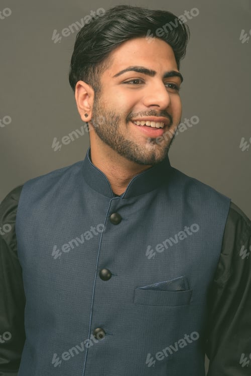 Preview: Young handsome Indian businessman against gray background