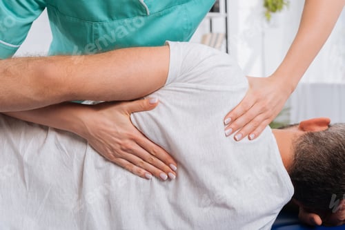 Preview: cropped shot of chiropractor massaging back on patient on massage table in hospital