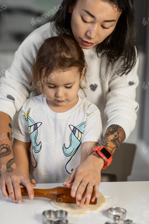 Preview: a little girl and her mother cook shortbread cookies using curly tin molds