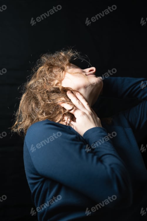 Preview: Sensual ginger model posing for a studio portrait, on a black background and studio light.
