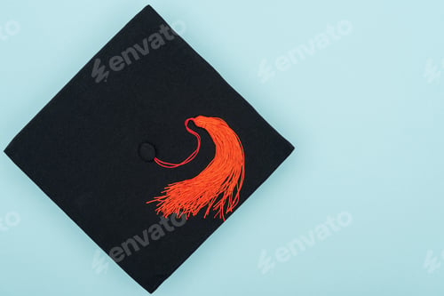 Preview: Top view of academic cap with red tassel isolated on blue