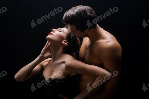Preview: Sexy woman in corset standing back to handsome shirtless man isolated on black