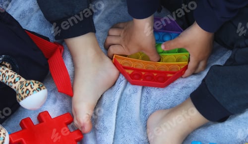 Preview: Pop it silicone anti-stress toy. The child plays on the grass. New trend Selective focus.
