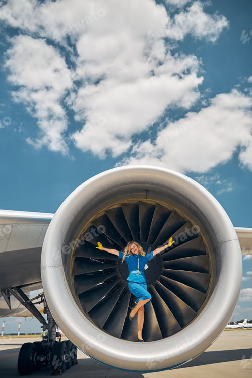 Preview: Beautiful young stewardess standing on plane engine