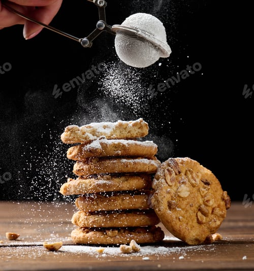 Preview: stack of baked round cookies sprinkled with powdered sugar on a wooden table, black background