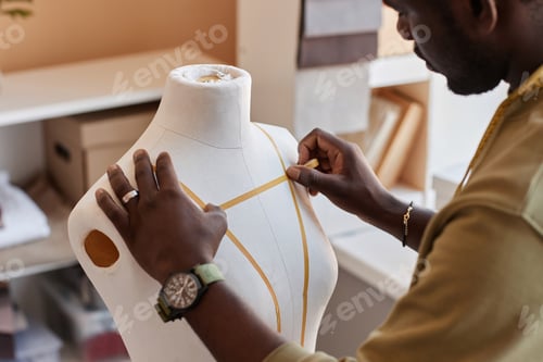 Preview: Hands of African American fashion stylist sticking tape on dummy