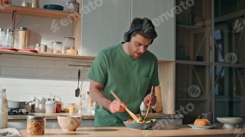 Preview: Guy earphones preparing food dancing along favorite song at kitchen closeup