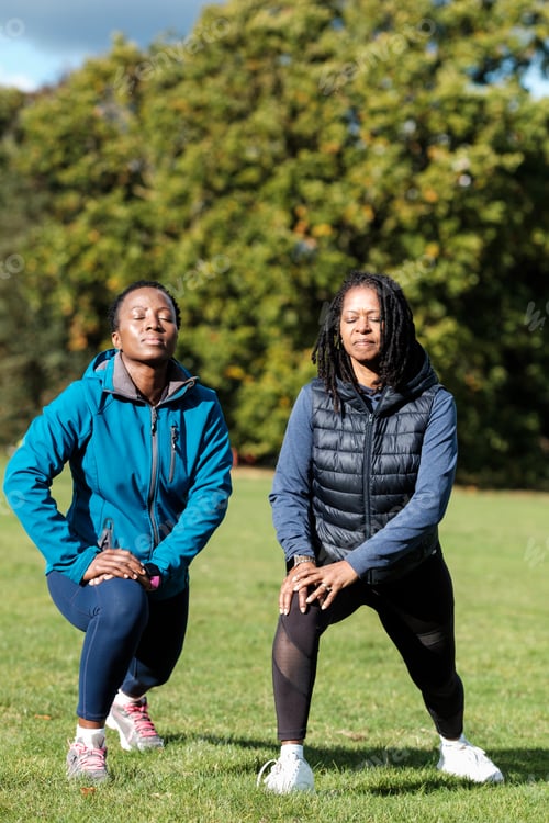 Preview: Mature black women doing exercise in a park. They are stretching legs and getting ready for a run.