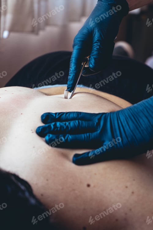 Preview: Vertical shot of a masseur with gloves using a physio hook on the back of a man