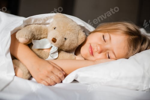 Preview: little blonde girl sleeping in bed hugging a teddy bear