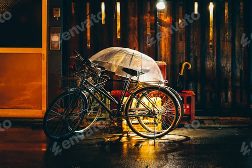 Preview: Wide shot of black road bicycles on the street with a clear umbrella on a rainy evening