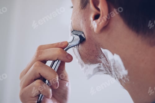 Preview: Young man shaving with a razor