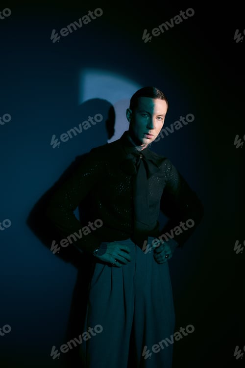 Preview: Stylish young man showcases fashion elegance against a dramatic dark backdrop