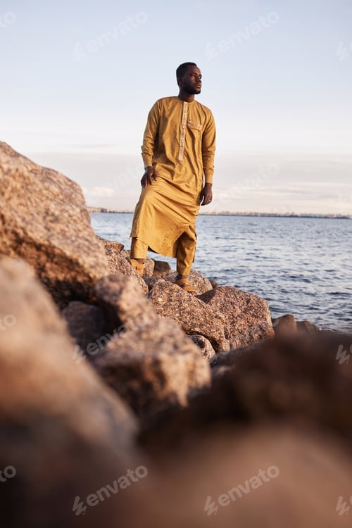 Preview: Black man walking along rocky sea shore