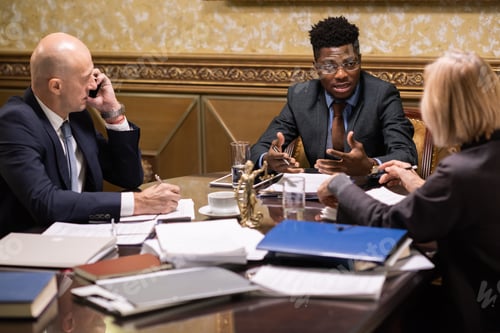 Preview: Confident young African businessman talking to mature female colleague