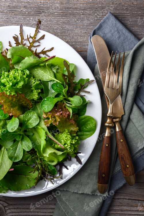 Preview: Fresh salad greens served with cutlery on rustic background