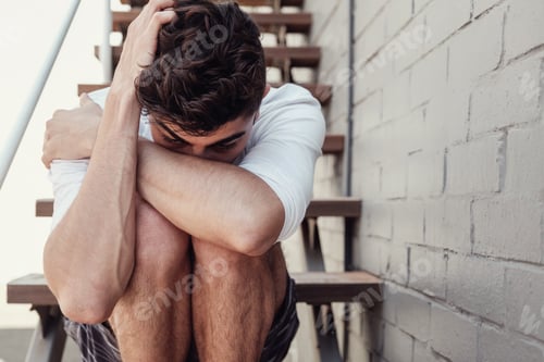Preview: Depressed young adult man sitting alone, mental health concept