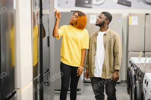 Preview: African american family couple buying domestic refrigerator in supermarket